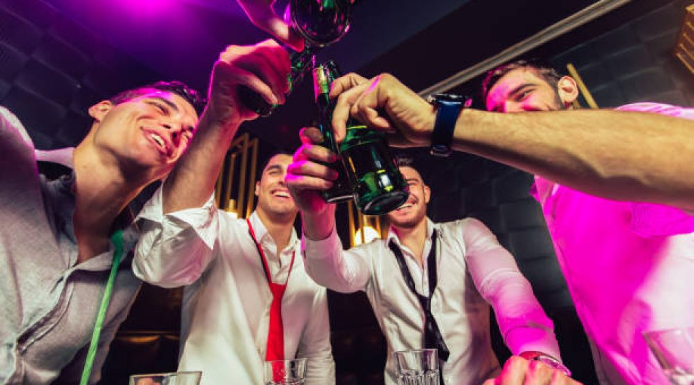 Group of smiling male friends having fun in night club